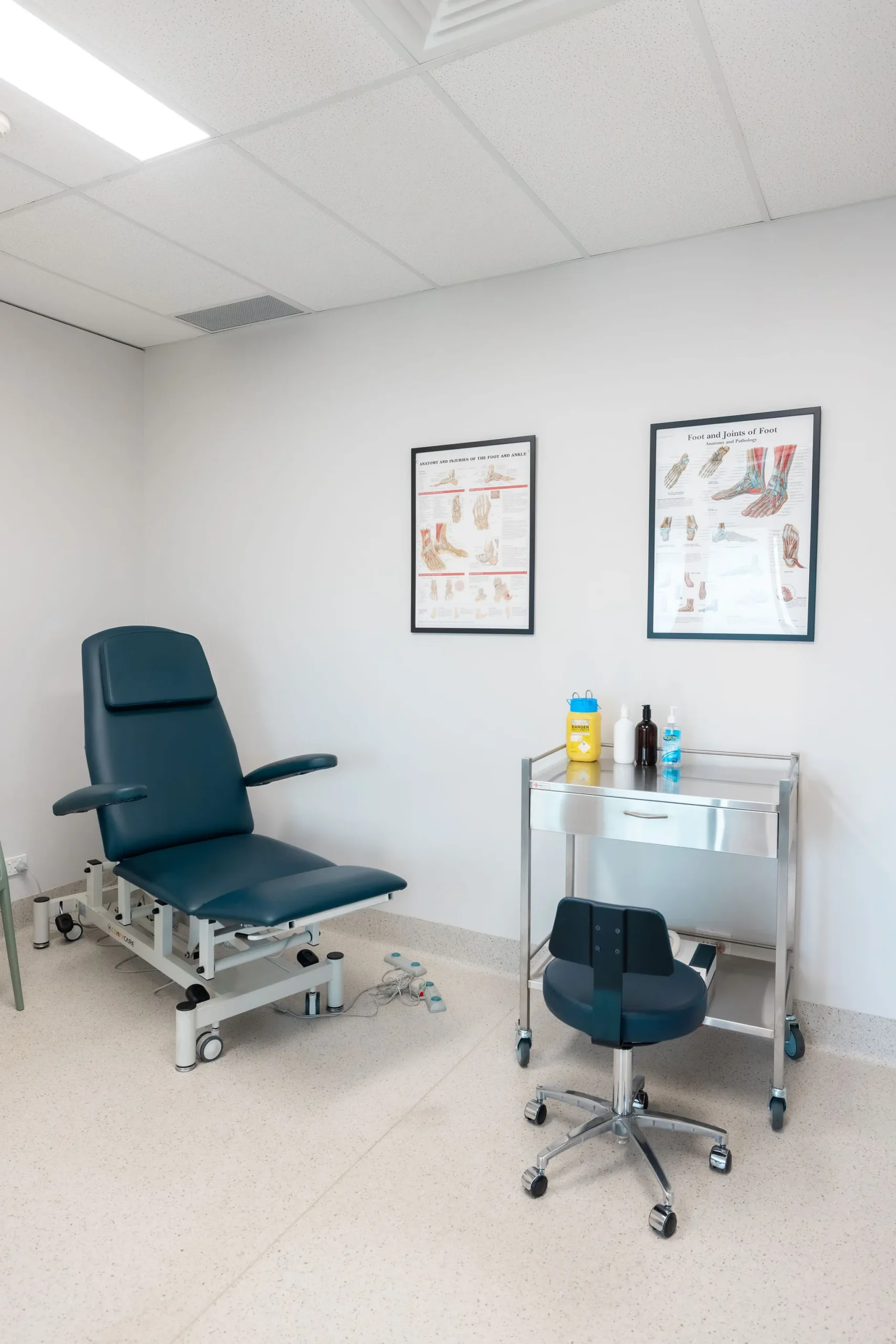 austral podiatry treatment room featuring examination chair, stool, and foot anatomy charts in podiatry clinic in austral, nsw