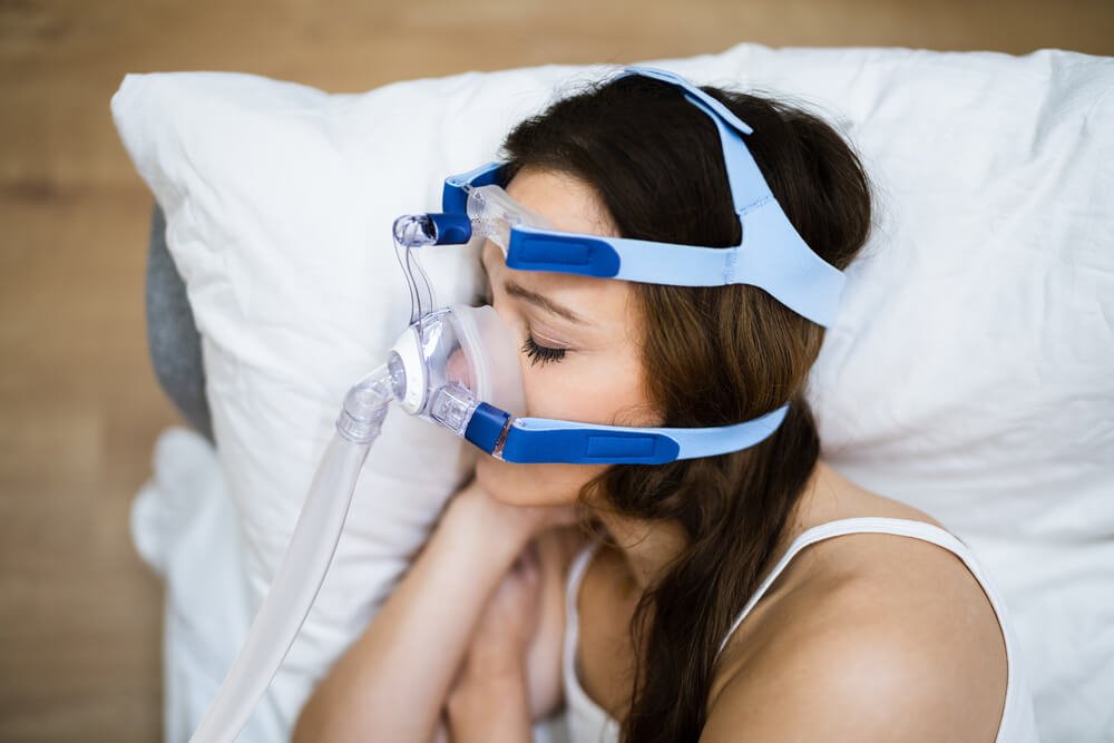 a woman with CPAP on while sleeping treating sleep apnea