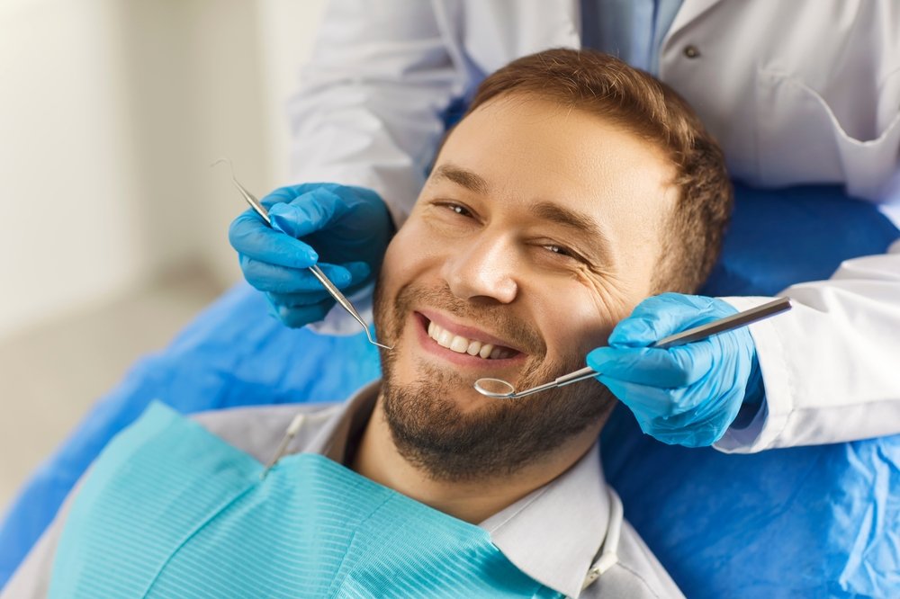 A modern dental office setting where a dentist is consulting with a patient about veneers. No text on the image.